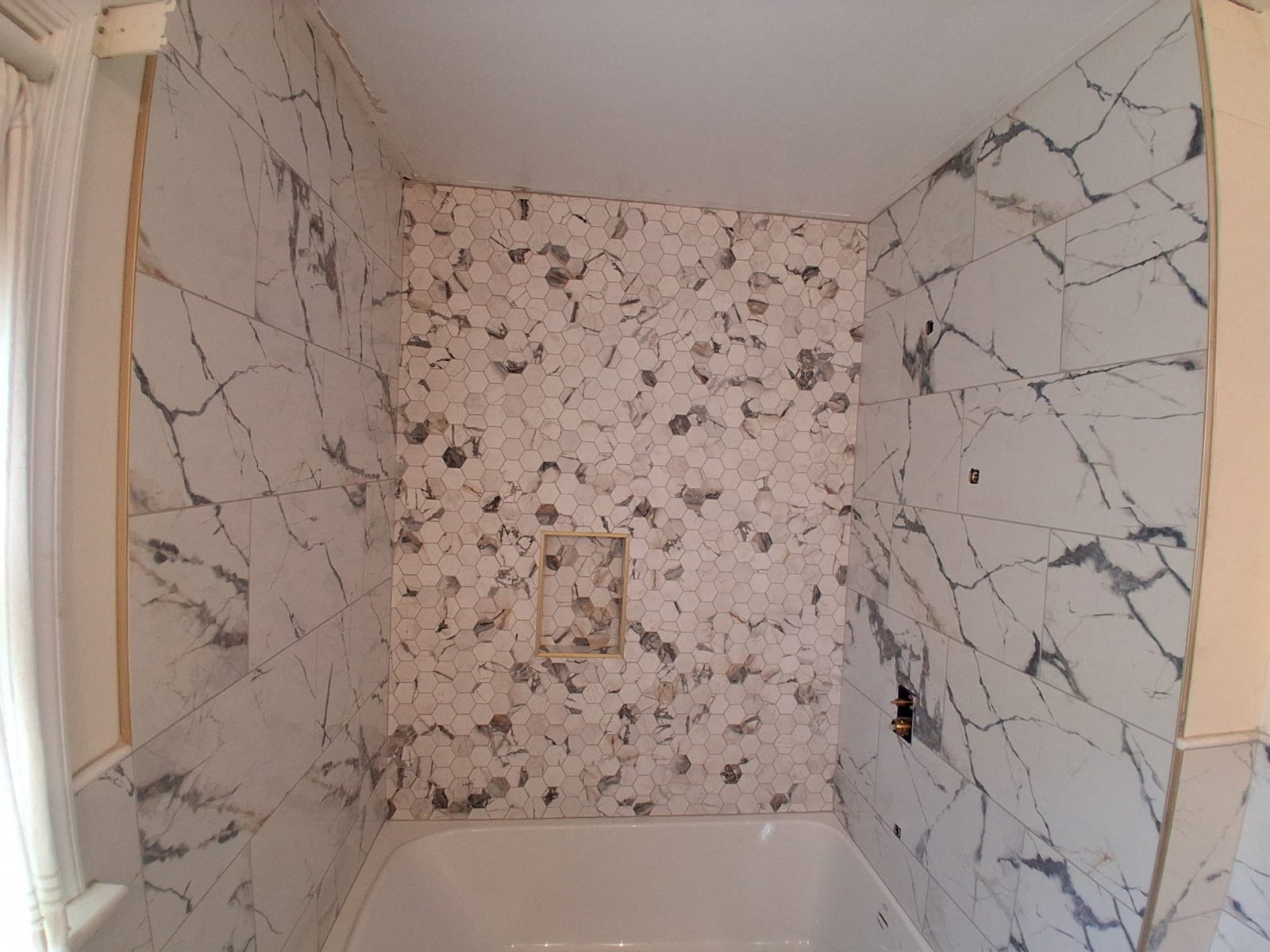 Full tiled shower with marble-look walls and mosaic accent